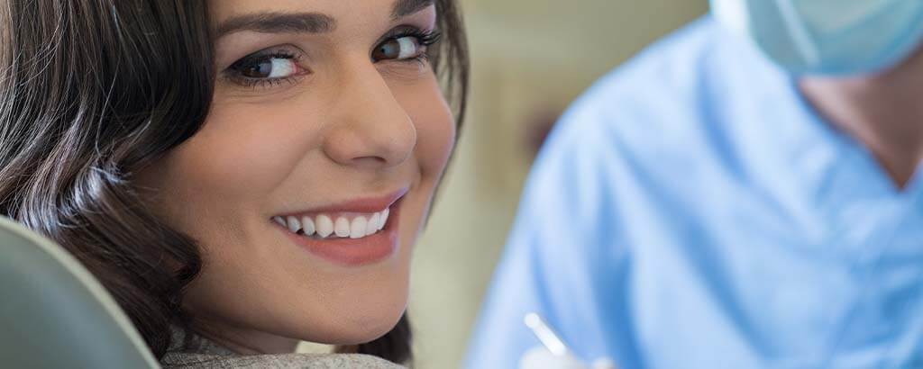 a woman smiles before receiving root canal retreatment